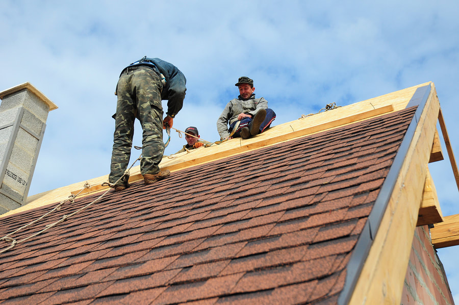 workers are installing roof shingles