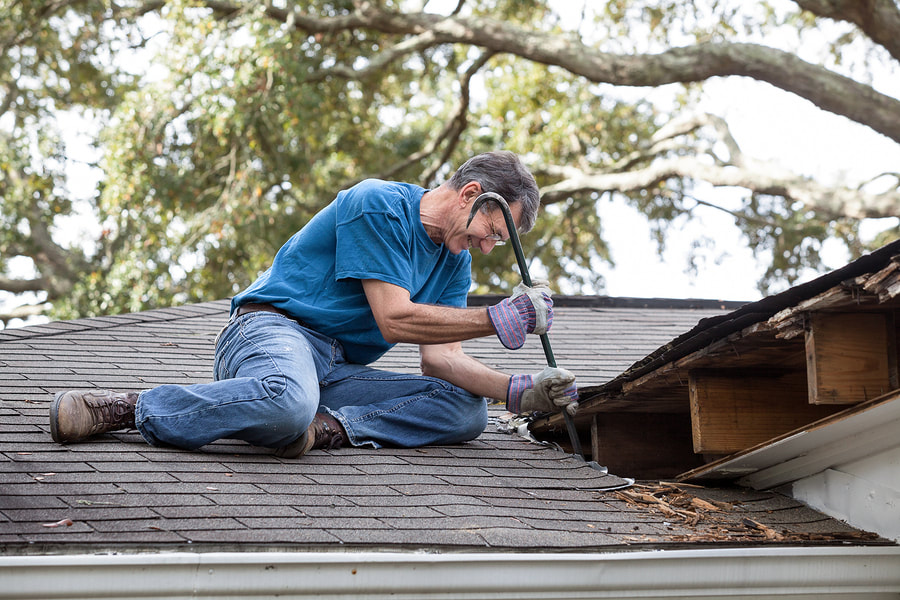 man repairing the house roof using cowbar